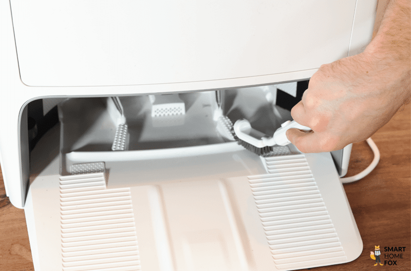 Die Wischwanne der ECOVACS DEEBOT T20 OMNI Station wird mit der Reinigungsbürste sauber gemacht.